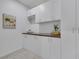 Bright laundry room featuring white cabinets, dark countertops, and a charming decorative floral painting at 1609 Dream Canyon Ave, North Las Vegas, NV 89084