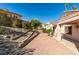Wide-angle view of the spacious backyard and home with desert landscaping and block retaining walls at 2037 Poppywood Ave, Henderson, NV 89012