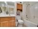 Bathroom featuring a shower-tub combo, oak vanity, and coordinating cabinet with a plant on top of the cabinet at 2037 Poppywood Ave, Henderson, NV 89012