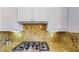 Close up on kitchen with gas range, granite backsplash, and white cabinetry at 25 Luce Del Sole # 3, Henderson, NV 89011