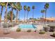 An eye-level view shows the community pool, sunshade structure, desert landscaping, and surrounding pink buildings at 2699 Aldonza Dr, Henderson, NV 89014