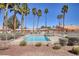 An eye-level view shows the community pool, sunshade structure, desert landscaping, and surrounding pink buildings at 2699 Aldonza Dr, Henderson, NV 89014