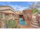 Backyard pool featuring rock waterfall and steps, surrounded by lush landscaping and a tan patio at 3221 Birdwatcher Ave, North Las Vegas, NV 89084
