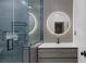 Bathroom featuring a tiled shower with glass door, round lighted mirror, and modern vanity at 6021 Vista Clara St, Las Vegas, NV 89148