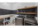 Laundry room with stainless steel washer and dryer, wooden shelves, and ample counter space at 6021 Vista Clara St, Las Vegas, NV 89148