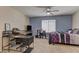 Spacious bedroom with a bed, desk, television, ceiling fan, and a combination of neutral and blue walls at 6457 Lovett Canyon St, Las Vegas, NV 89148