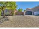 A gravel driveway with an iron gate leads to the garage and a home with well-maintained landscaping at 6527 Lokai Ave, Las Vegas, NV 89130