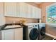 Convenient laundry room with modern washer, dryer, sink, and storage cabinets at 6527 Lokai Ave, Las Vegas, NV 89130