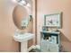 Powder room with a pedestal sink, decorative shelving, and an oval mirror at 6527 Lokai Ave, Las Vegas, NV 89130