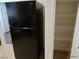A modern black refrigerator stands next to a well-organized pantry with wire shelves at 7255 W Sunset Rd # 2093, Las Vegas, NV 89113