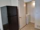 Appliance nook with tile floors features a black refrigerator and white stacked washer and dryer at 7255 W Sunset Rd # 2093, Las Vegas, NV 89113