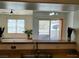 View of the living room and balcony from the kitchen features hardwood flooring, neutral walls, and large windows at 7255 W Sunset Rd # 2093, Las Vegas, NV 89113