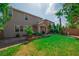 A well-kept backyard with a green lawn, tropical trees, covered patio, and a swing set at 7837 Hamilton Pool Dr, Las Vegas, NV 89113