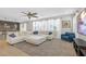 Spacious living room with large sectional, ceiling fan, and adjoining kitchen view at 7837 Hamilton Pool Dr, Las Vegas, NV 89113