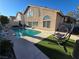 Inviting backyard with a sparkling pool, a comfortable hanging chair, and well-manicured landscaping at 8401 Luna Bay Ln, Las Vegas, NV 89128
