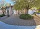 Well-manicured front yard with desert landscaping, mature trees, and charming decorative elements at 8401 Luna Bay Ln, Las Vegas, NV 89128
