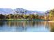 A serene lake reflects the mountains and community structures, lined with trees and walking paths at 8401 Luna Bay Ln, Las Vegas, NV 89128
