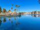 A serene lake offers picturesque community views with clear blue waters reflecting palm trees, houses, and mountains at 8401 Luna Bay Ln, Las Vegas, NV 89128