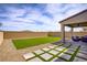 Landscaped backyard featuring artificial turf, decorative stone, and a covered patio with stylish outdoor furniture at 8564 Scalpay St, Las Vegas, NV 89166