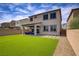 Two-story home showcasing a spacious backyard with artificial turf and a covered patio seating area at 8564 Scalpay St, Las Vegas, NV 89166