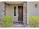 Close up of a well landscaped home entrance with stone accents around the door and a decorative light fixture at 8564 Scalpay St, Las Vegas, NV 89166