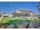 The backyard includes a putting green, covered patio with BBQ, dining area, and comfortable seating around a firepit at 8725 Hawk Canyon St, Henderson, NV 89074