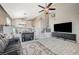 This living room has a vaulted ceiling, a ceiling fan, stairs with patterned risers and a large TV screen at 8725 Hawk Canyon St, Henderson, NV 89074