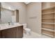 Modern bathroom with a dark vanity cabinet, white countertop, toilet, open shelving, and large mirror at 1541 Unison Way # 102, Las Vegas, NV 89135