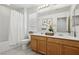 Well-lit bathroom with double sink vanity, tiled floors, bathtub with shower, and a decorative floral arrangement at 160 Lilt Ave, Henderson, NV 89011