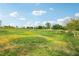 Expansive community park with green spaces, walking paths, mature trees, and benches under a blue sky with clouds at 160 Lilt Ave, Henderson, NV 89011