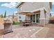 Inviting outdoor patio with brick pavers, dining set under an umbrella, and grill for entertaining at 160 Lilt Ave, Henderson, NV 89011