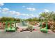 Community playground featuring swings, climbing structures, lush landscaping, and walking path under a sunny blue sky at 160 Lilt Ave, Henderson, NV 89011