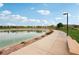 Community pond featuring a walking path, bench seating, native plants, and a security fence against a blue sky at 160 Lilt Ave, Henderson, NV 89011