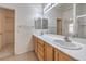 Bright bathroom with double sinks, wood cabinets, and a view of the walk-in closet and shower at 3520 Kittiwake Rd, North Las Vegas, NV 89084