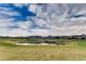 Beautiful view of the golf course with a pond and green fairways under a bright blue, cloudy sky at 39 Strada Fontana, Henderson, NV 89011