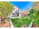 Spacious backyard with a well-maintained lawn, partially covered patio, and mature trees at 4921 Lazy Day Ct, Las Vegas, NV 89131