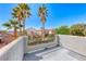 Second story balcony with stucco wall, metal railing, and views of mature palm trees and neighborhood rooftops at 4921 Lazy Day Ct, Las Vegas, NV 89131
