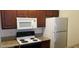 Kitchen with an electric stove, white microwave and refrigerator, and dark wood cabinets at 5158 S Jones Blvd # 107, Las Vegas, NV 89118