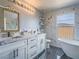 Bright bathroom featuring double sinks, designer mirror, black hardware, and large window above soaking tub at 5364 Awbury Ave, Las Vegas, NV 89110