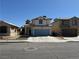 Two story home with blue garage door, desert landscaping, and light colored stucco at 6297 Peach Orchard Rd, Las Vegas, NV 89142