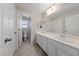 Bathroom with double sinks, a large mirror, and a door leading to a toilet and bathtub/shower area at 6403 Dundock Ave, Las Vegas, NV 89122