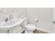 A clean bathroom featuring a white pedestal sink, toilet, and modern fixtures at 6952 Crimson Shadow St, North Las Vegas, NV 89086