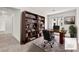 This staged office has a large bookcase and a workspace for a laptop and comfortable executive chair at 6952 Crimson Shadow St, North Las Vegas, NV 89086