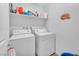 Well-organized laundry room with washer, dryer, shelving, and camping-themed decor at 6952 Crimson Shadow St, North Las Vegas, NV 89086