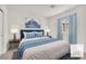 The staged main bedroom features an accent wall with paintings, window, and blue bedding at 6952 Crimson Shadow St, North Las Vegas, NV 89086