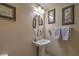 Charming powder room features a pedestal sink, decorative mirror, and textured walls at 7311 Velvet Sky St, Las Vegas, NV 89131