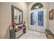 Inviting foyer featuring elegant console table with mirror, tile flooring, a decorative front door, and neutral wall paint at 7311 Velvet Sky St, Las Vegas, NV 89131
