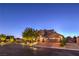 A beautiful exterior view of a home with brick-paved driveway, a mature tree and elegant landscaping in a well-lit cul-de-sac at 7311 Velvet Sky St, Las Vegas, NV 89131