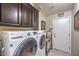 Well-lit laundry room features a modern washer and dryer, tile floor, and ample cabinet storage at 7311 Velvet Sky St, Las Vegas, NV 89131