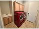 Functional laundry room with cabinets, sink, and modern red washer and dryer at 8370 Unicorn St, Las Vegas, NV 89131